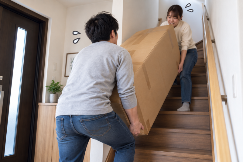 夫婦で梱包された家具を2階へ運び上げる様子